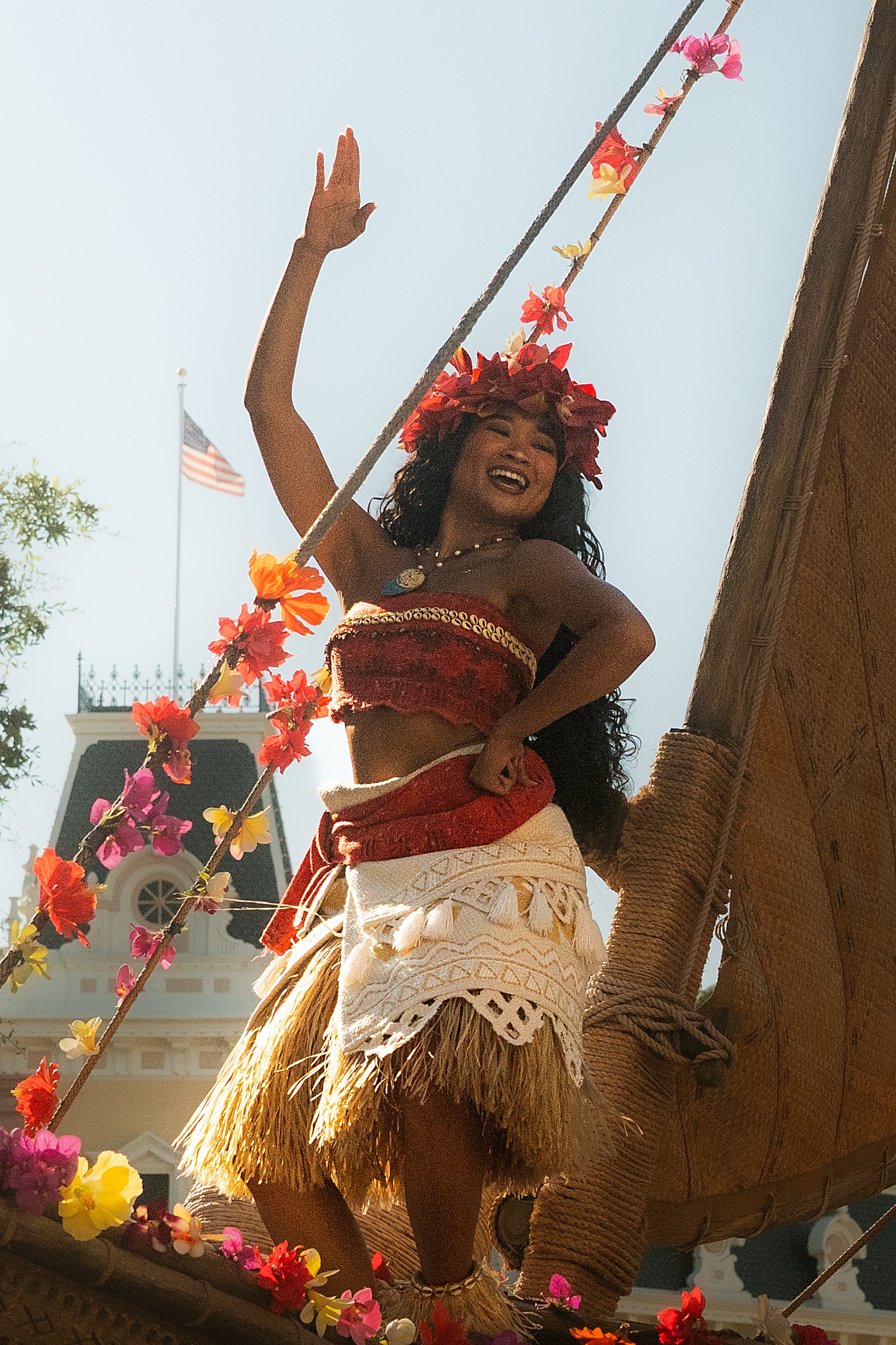 Kamryn Hernandez in character as a Disney princess, waving from a decorated canoe during a theme park parade